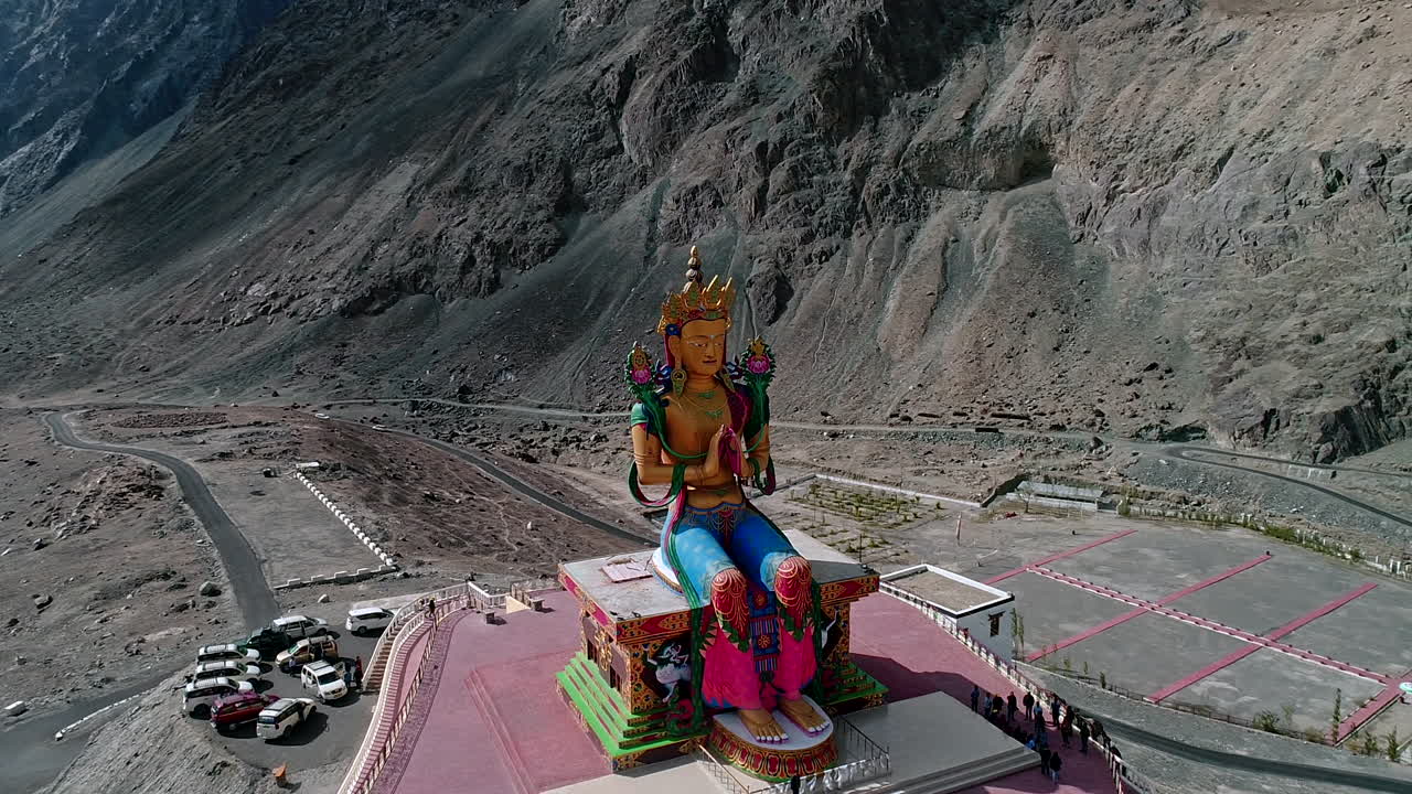 imágenes aéreas de un dron dando vueltas alrededor de una estatua dorada de buda en ladakh.