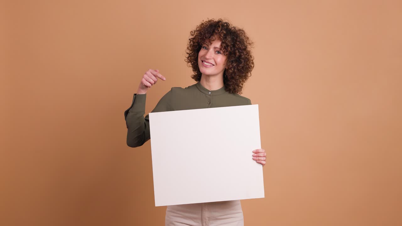 Happy woman holding blank paper in beige studio