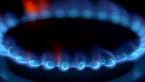 methane firing up with blue flame on gas stove burner in total dark room. 4k