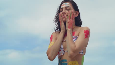 On-a-sunny-Caribbean-day,-a-girl-in-body-paint-and-a-bikini-along-a-white-sand-beach-facial-close-up