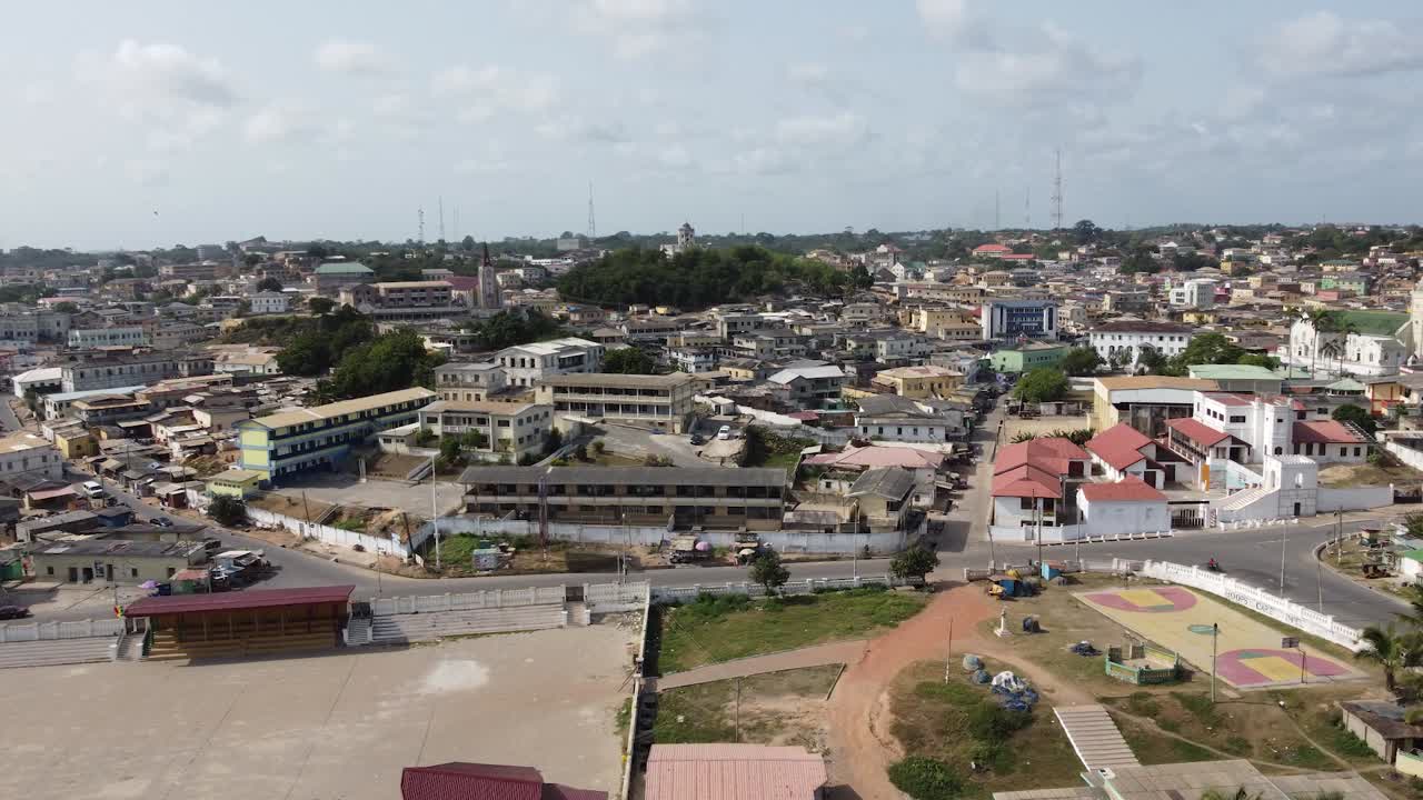 Vista aérea ensolarada de Cape Coast, Gana, mostrando uma praia dourada, ondas oceânicas e água azul cristalina ao longo da costa atlântica, capturando a atmosfera costeira vibrante da África