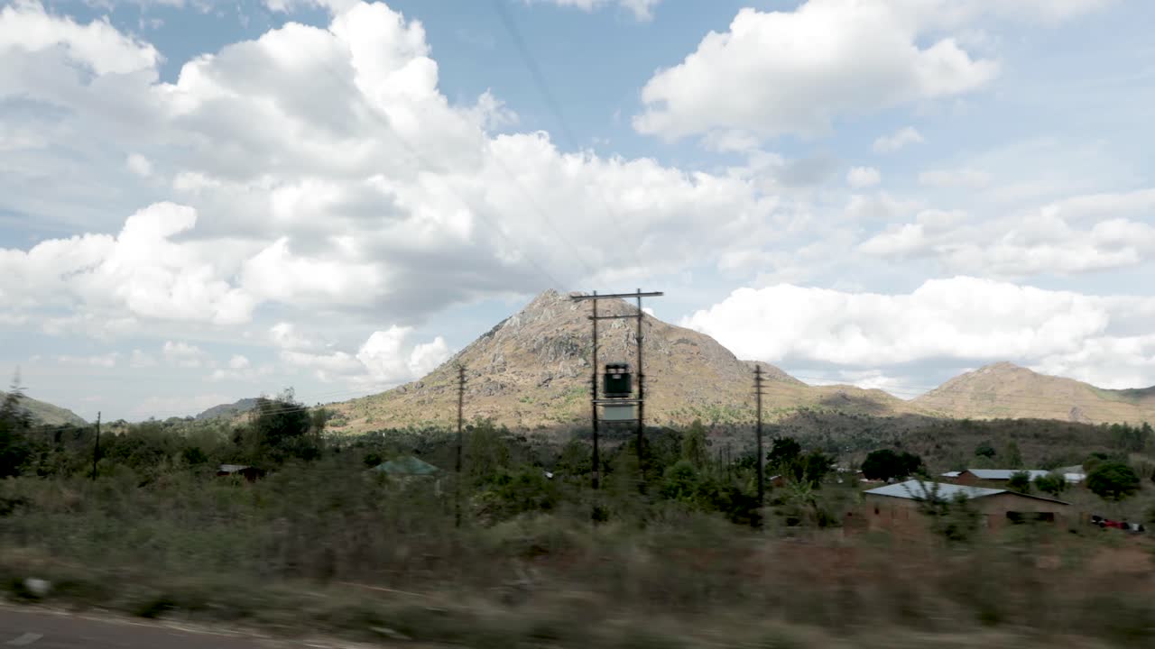 viajando por una carretera en malawi áfrica con una ciudad y vehículos pasando, vista desde el avance del vehículo