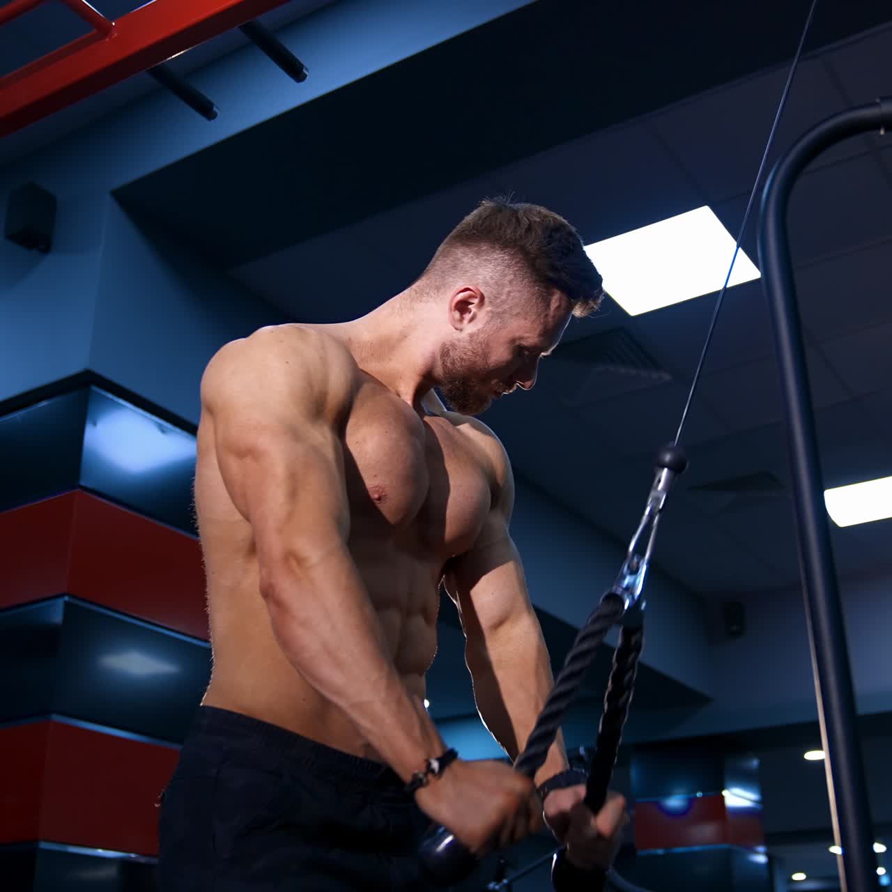 Forte bodybuilder muscoloso si allena in una palestra moderna. Allenamento per le mani su attrezzature sportive. Movimento lento