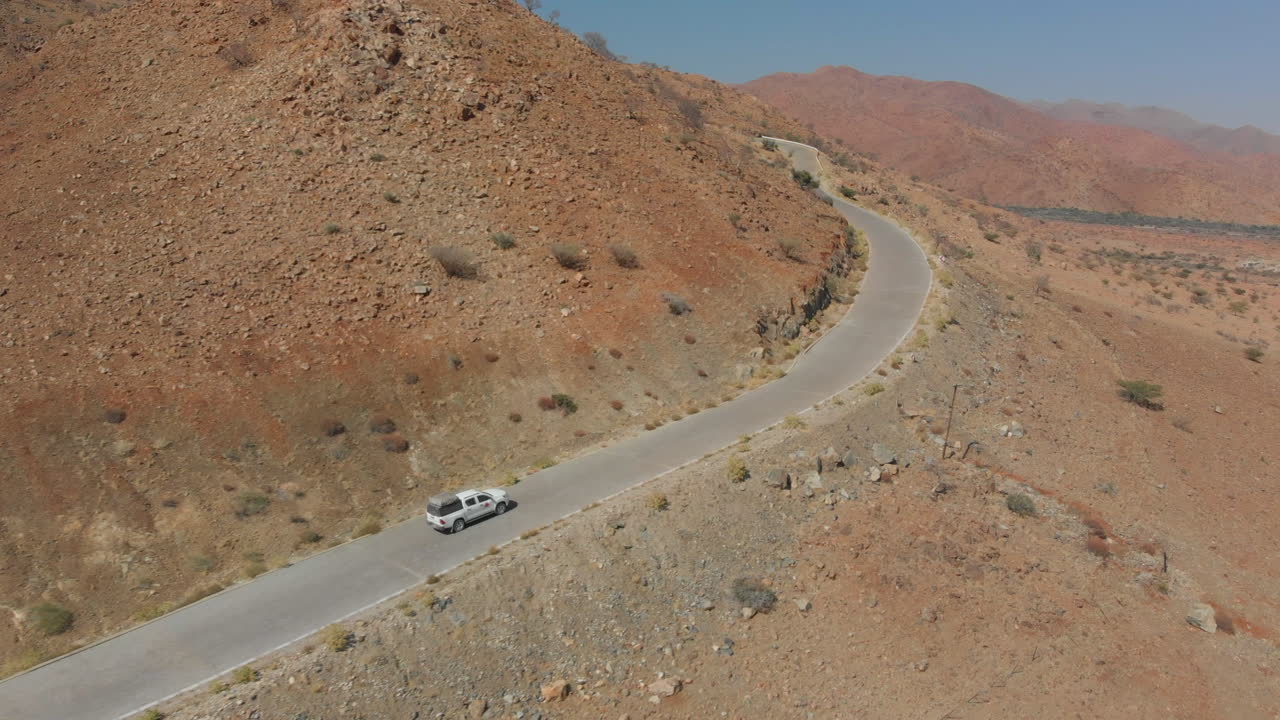 antena siguiendo el coche que viaja por un camino empinado en las montañas del desierto