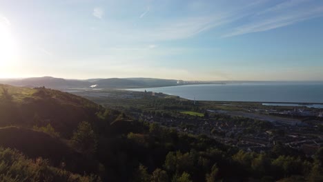 Coastal-Aerial-View-of-Ocean,-Houses-and-Steelworks-in-Distance