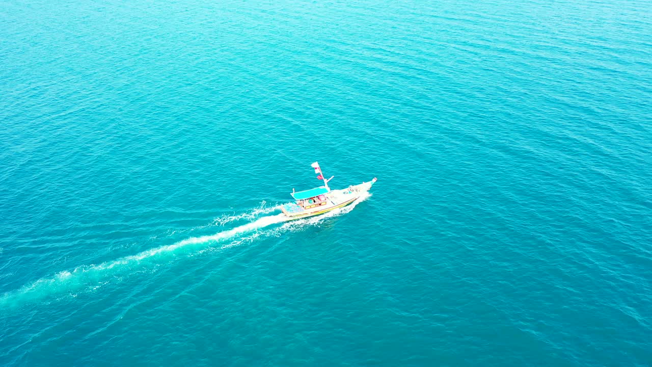 Touring boat sailing slowly across azure sea surface with vibrant water reflecting bright blue sky over tropical islands