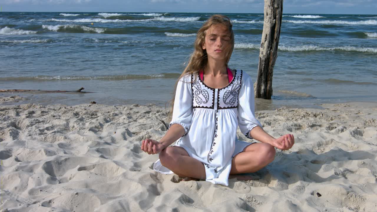 Woman trains breath practicing yoga and meditation on the sea beach