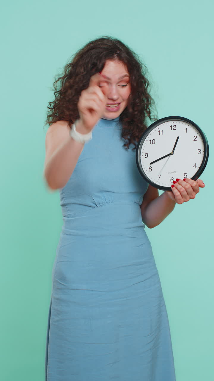 Woman showing time on wall office clock ok thumb up approve pointing finger at camera your time