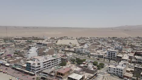 aerial: small pacific town of paracas peru in endless sandy desert