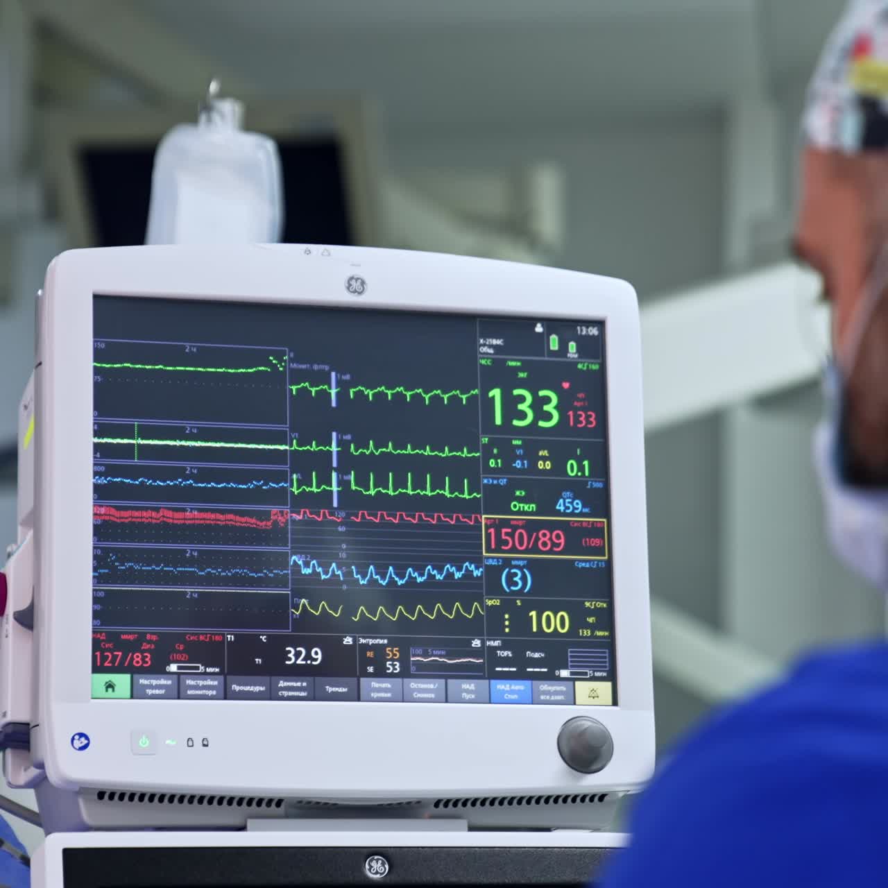 Male anesthesiologist looks at the screen of lung ventilator. Medic monitoring the condition of a patient during surgery