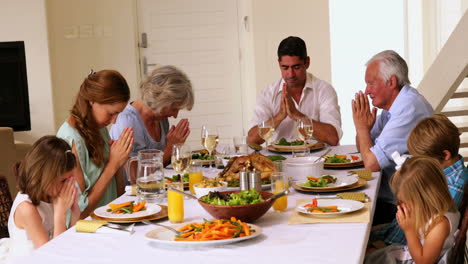 extended family praying together before dinner