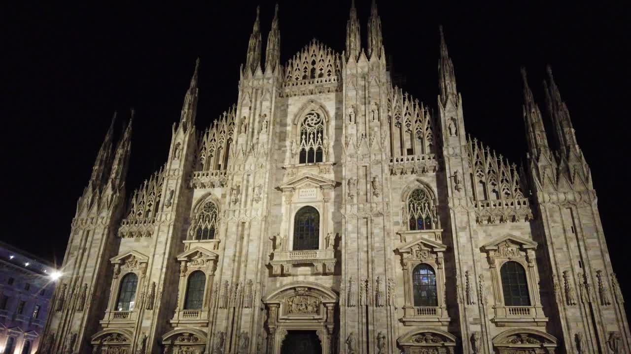Milan duomo cathedral at night tilt down view of the main facade illuminated at nighttime