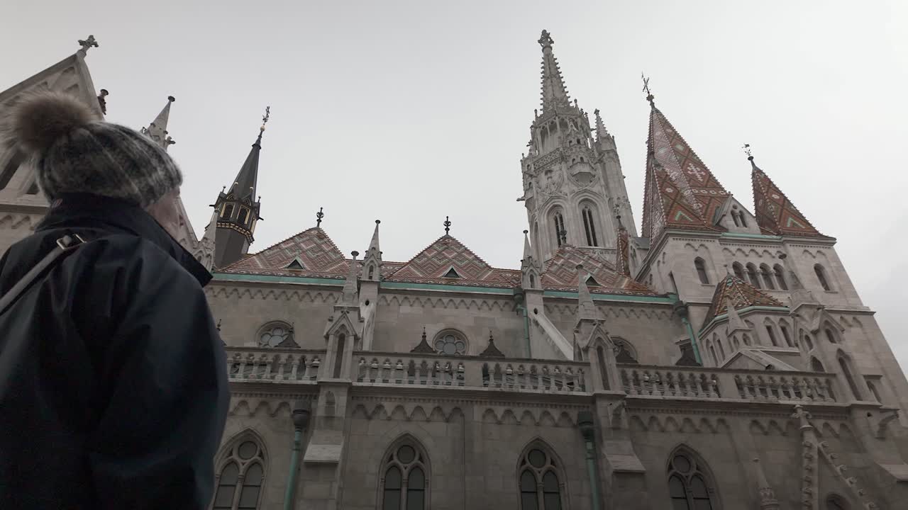 Low angle: Woman admires Gothic architecture, Matthias Church Budapest