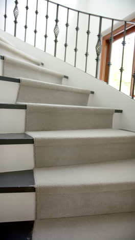 vertical video of spiral staircase in hallway of luxury home, slow motion