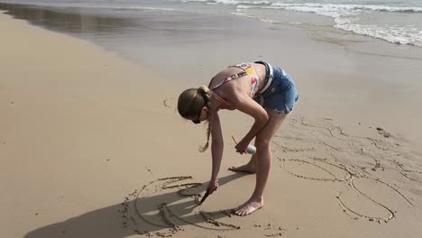 woman drawing in the sand on the beach