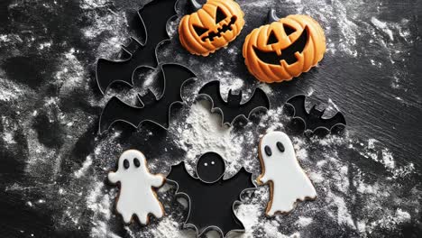 halloween cookie cutters and decorated cookies on floured surface