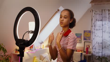 teenage girl making a video with ring light in her room.