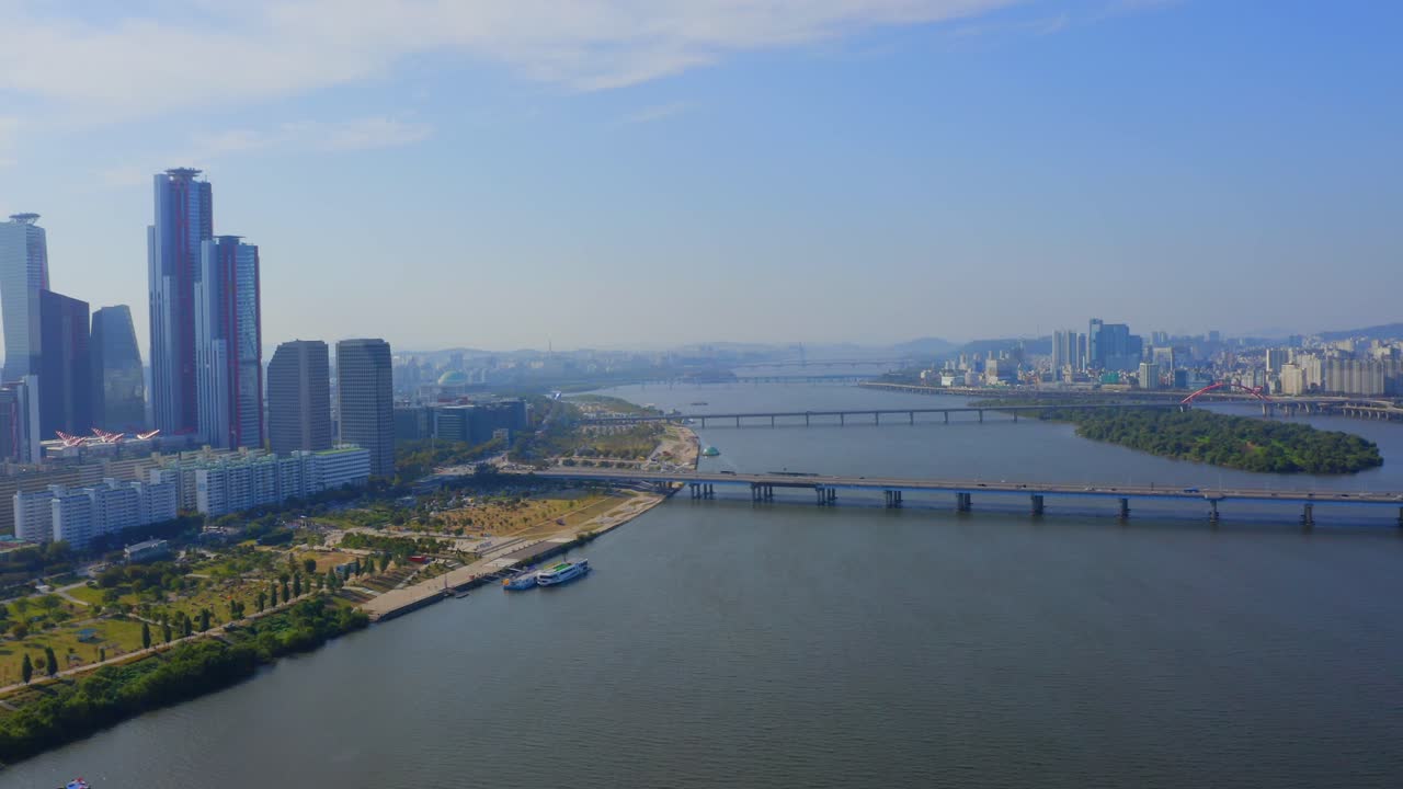 화창한 날 서울의 고층 빌딩이 있는 마포대교와 상업 지구를 향해 한강 위로 앞으로 이동하는 드론 샷