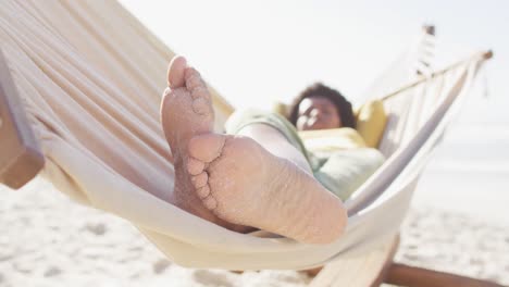 Glückliche-Afroamerikanische-Frau,-Die-In-Der-Hängematte-Am-Sonnigen-Strand-Liegt