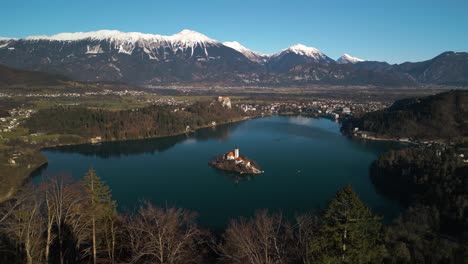 drone flies away from lake bled, slovenia to reveal forest