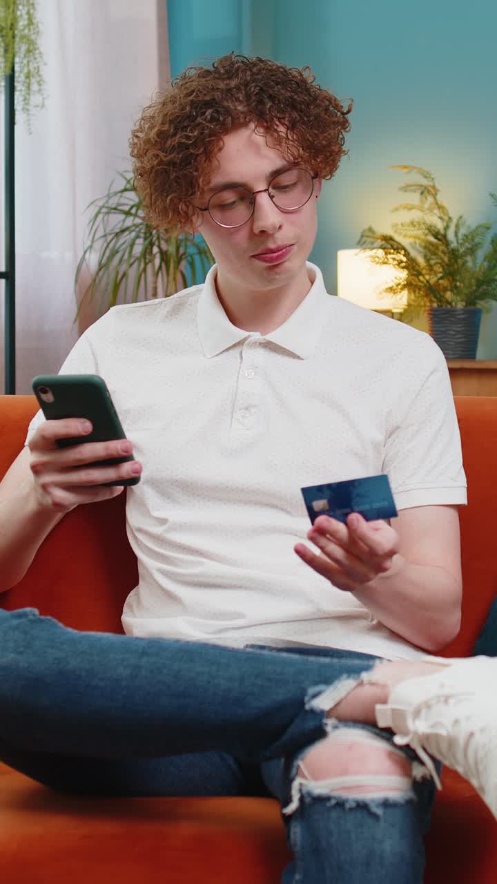 Uomo che usa la carta di credito e lo smartphone mentre trasferisce denaro acquista online a casa