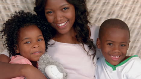 Mother-and-children-smiling-at-camera-in-bed