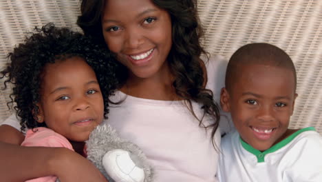 mother and children smiling at camera in bed