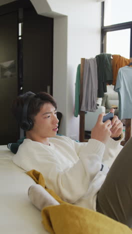 아시안 남성 십대가 거실에서 비디오 게임을 하는 수직 비디오