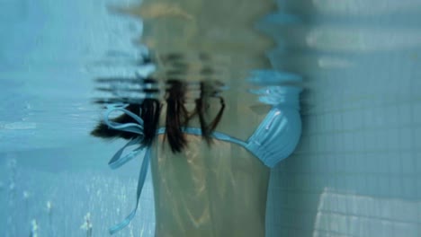 Underwater-view-of-woman-leaning-on-edge-of-pool