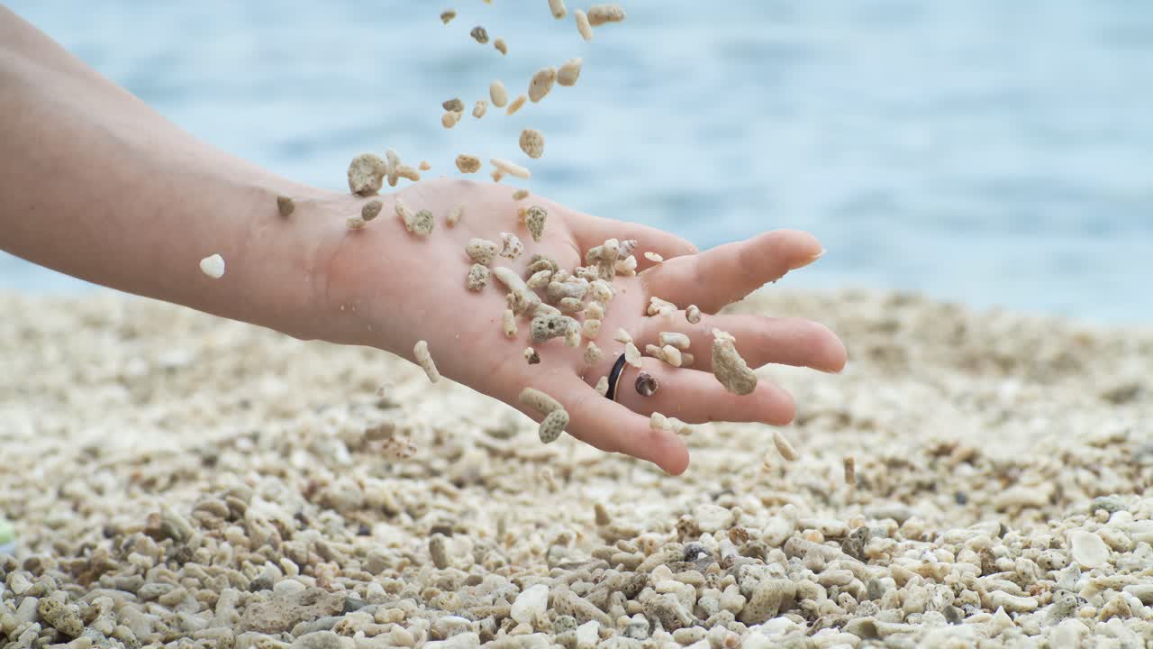 Coral Sand falling from hand in slow motion on a coral beach. Vacation and travel concept. Shot on super slow motion camera 1000 fps.