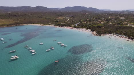 aerial view of a vibrant turquoise beach with boats and people