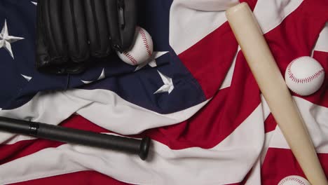 vida muerta de béisbol con bate y pelota en la bandera estadounidense con una persona recogiendo el guante de receptores