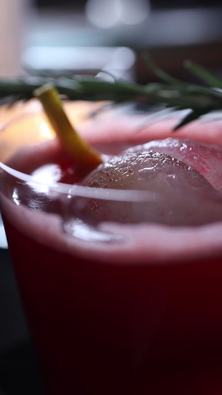 primer plano de un refrescante cóctel rojo con romero y limón