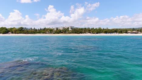 Low-angle-aerial-dolly-shot-of-Caribbean-waters-and-beautiful-beach