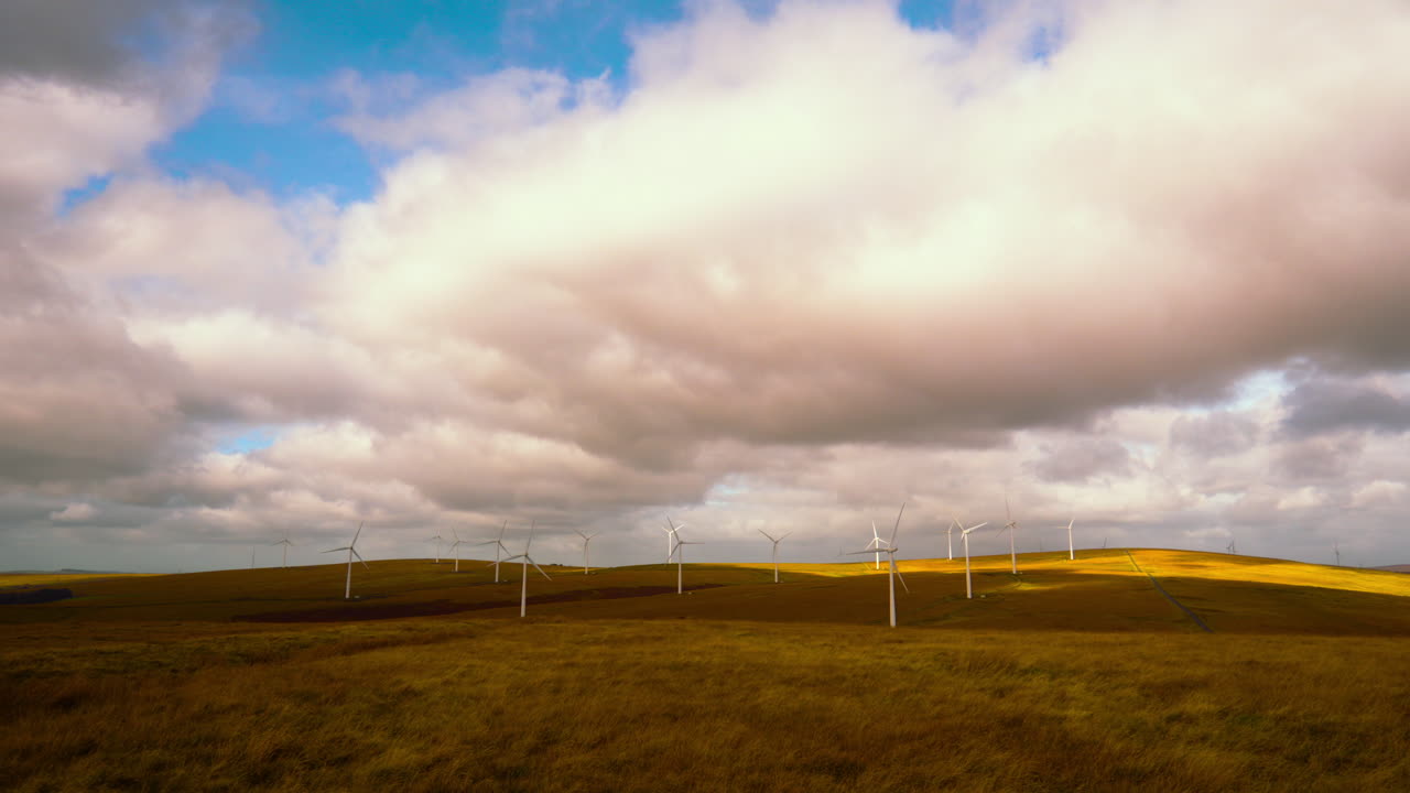 Wide View of Wind Farm in Wales with Bright Clouds with Blue Sky Behind. Renewable Sustainable Energy Technology