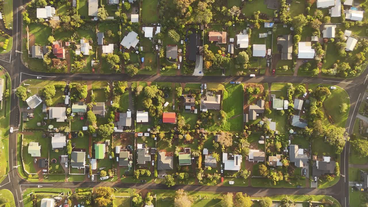Houses in Oneroa, Waiheke Island, bathed in sunset light, New Zealand. Aerial forward directly above