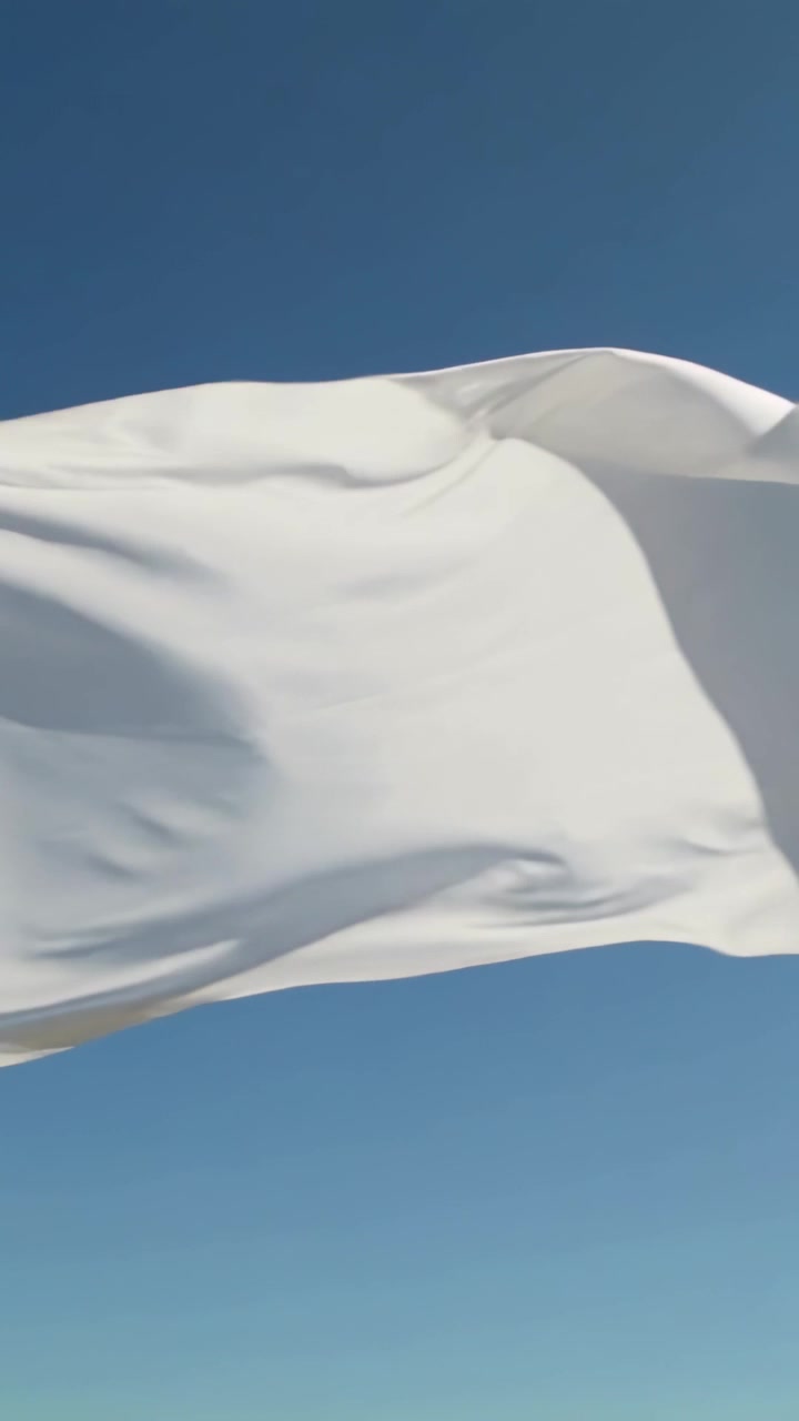 Video vertical: Bandera blanca ondeando y desplegándose, agitándose en el cielo azul claro por una brisa constante.
