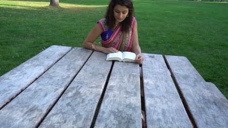mujer joven en sari leyendo un libro