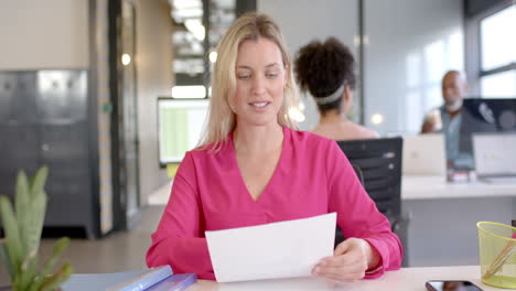 caucasian businesswoman reading document in office with copy space