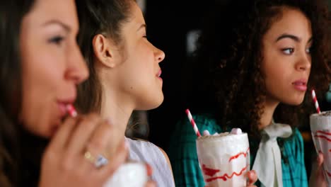 smiling female friends having smoothie with straw