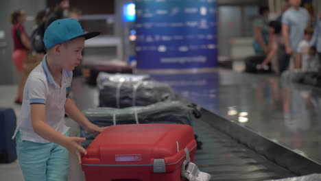 boy looking for his suitcase on baggage conveyor belt at the airport