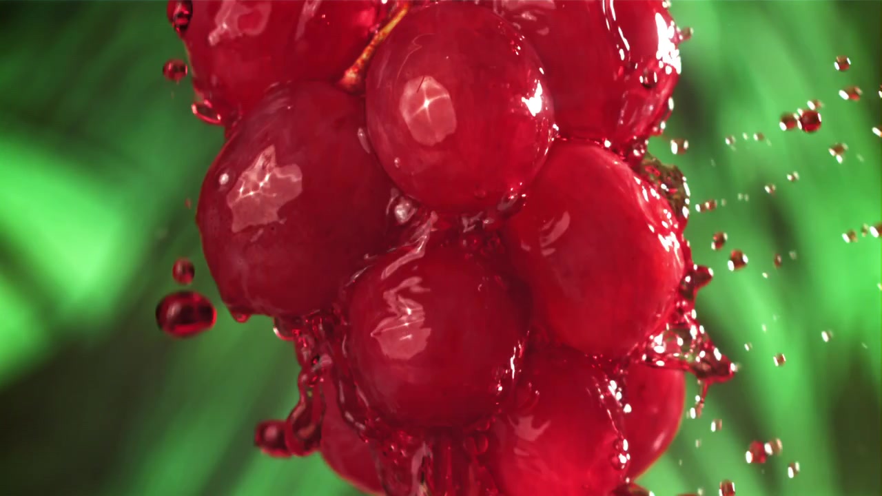 Slow Motion Red Grapes Splashing with Water on Green Background