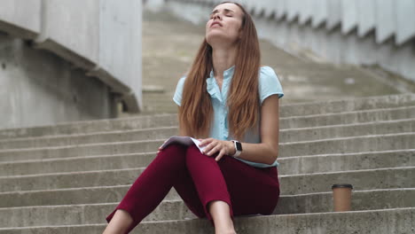 Businesswoman-sitting-on-stairs-with-papers.-Professional-meditating-on-street