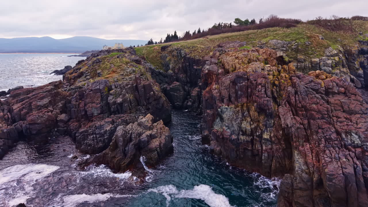 La costa rocciosa mette in mostra scogliere imponenti e onde delicate sotto un cielo nuvoloso vicino alla riva, invitando gli amanti della natura a esplorare e ammirare la bellezza dell'oceano.