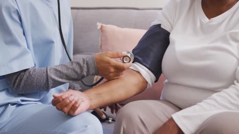 mixed race woman being visited at home by a nurse. social distancing and self isolation in quarantin