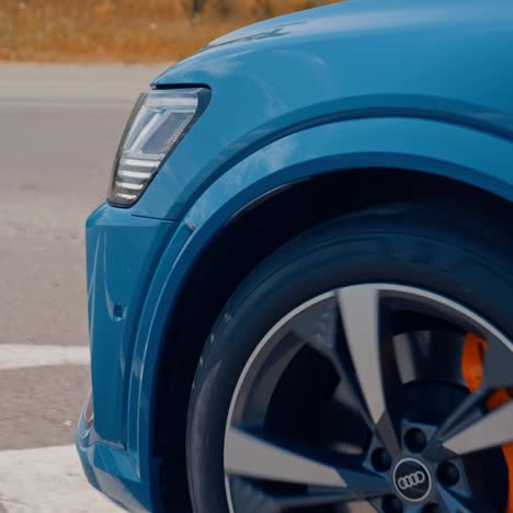 Close-up view on the side part of a car and a wheel at moving the road. Wheel of luxury white car turning slowly on asphalt road