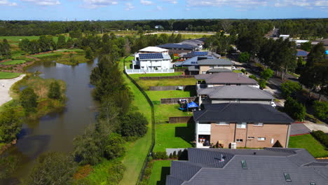 Toma-Aérea-De-Grandes-Casas-Australianas-Junto-A-Un-Lago-Ocupado-Suburbio-Con-Tráfico