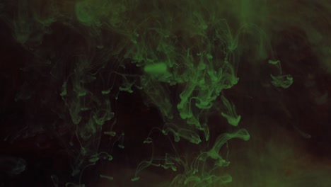 mezclando partículas de colores brillantes de pintura verde y roja en el humo.