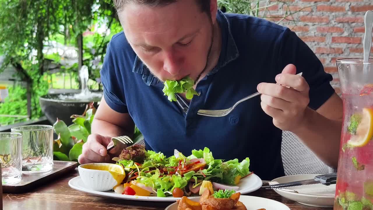 hombre comiendo una ensalada grande al aire libre