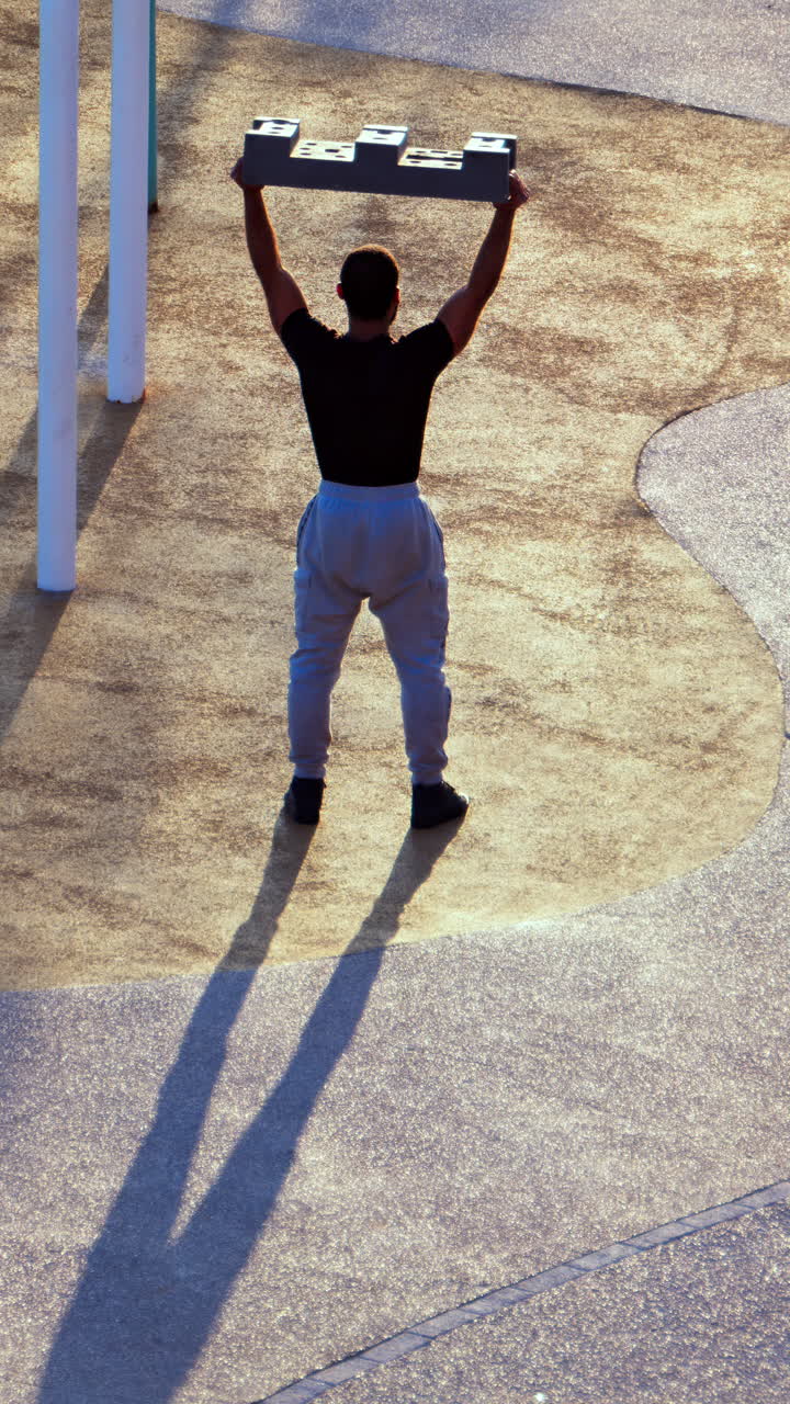 Man doing squats with a construction block on the beach. Vertical